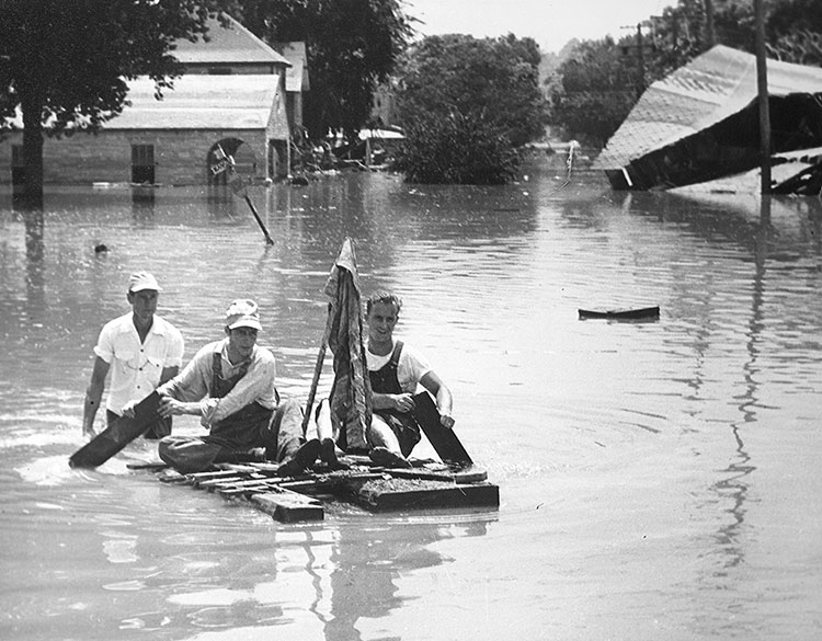 Men paddle a raft near Mill Street Bridge in Armourdale.